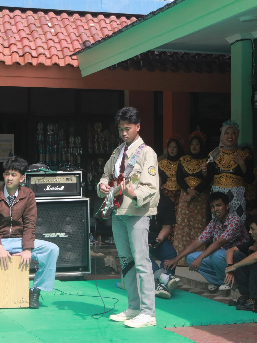 Playing a red electric guitar at a school performance