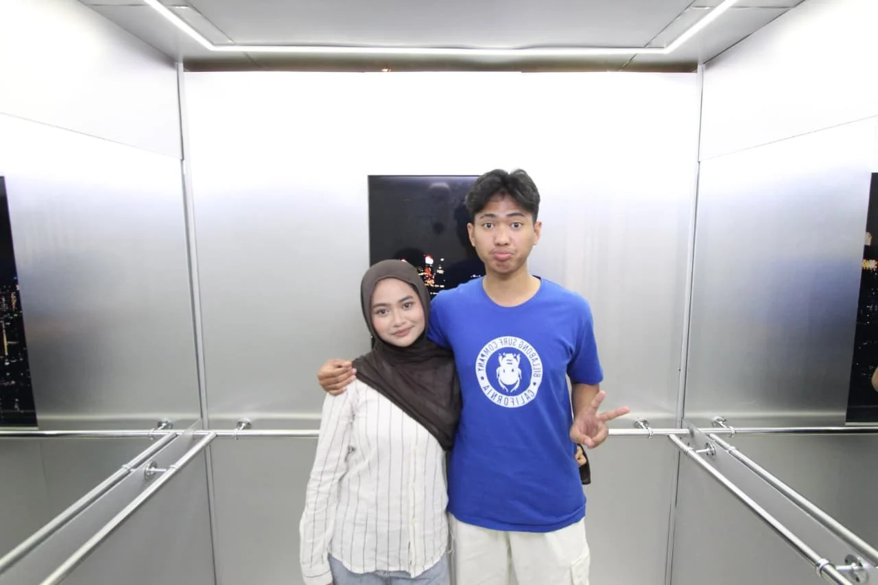 Standing together in an elevator, with an arm around her shoulder