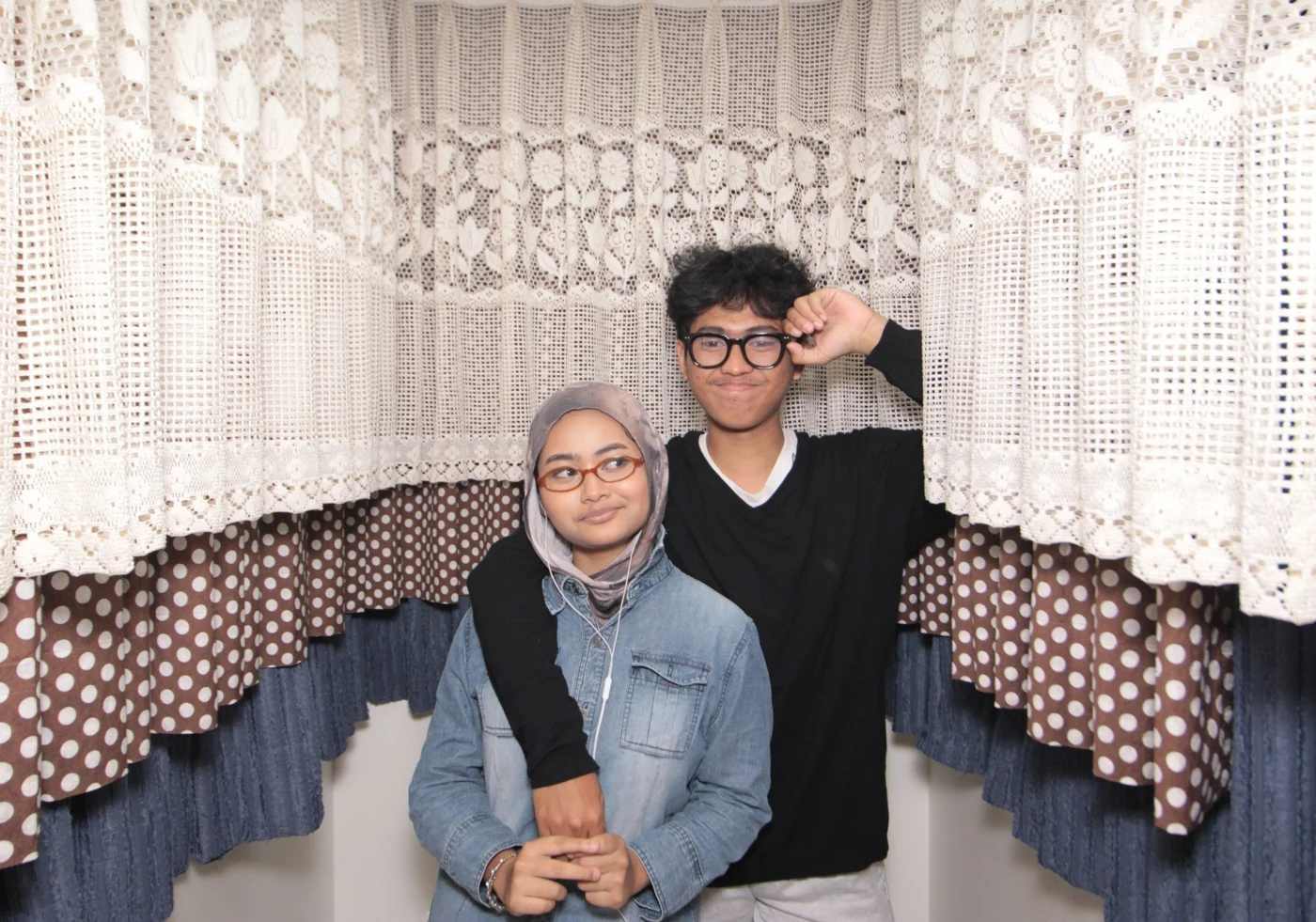 Standing together in a photo booth, both wearing glasses